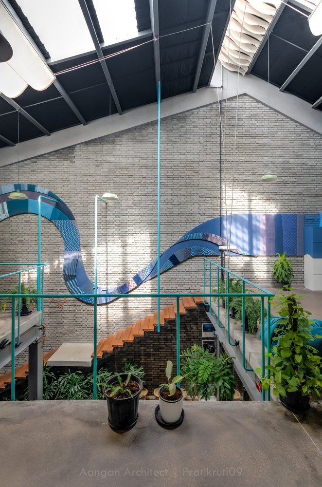 Atrium view showing the blue metal slide wrapping around brick walls and steel columns with daylight above