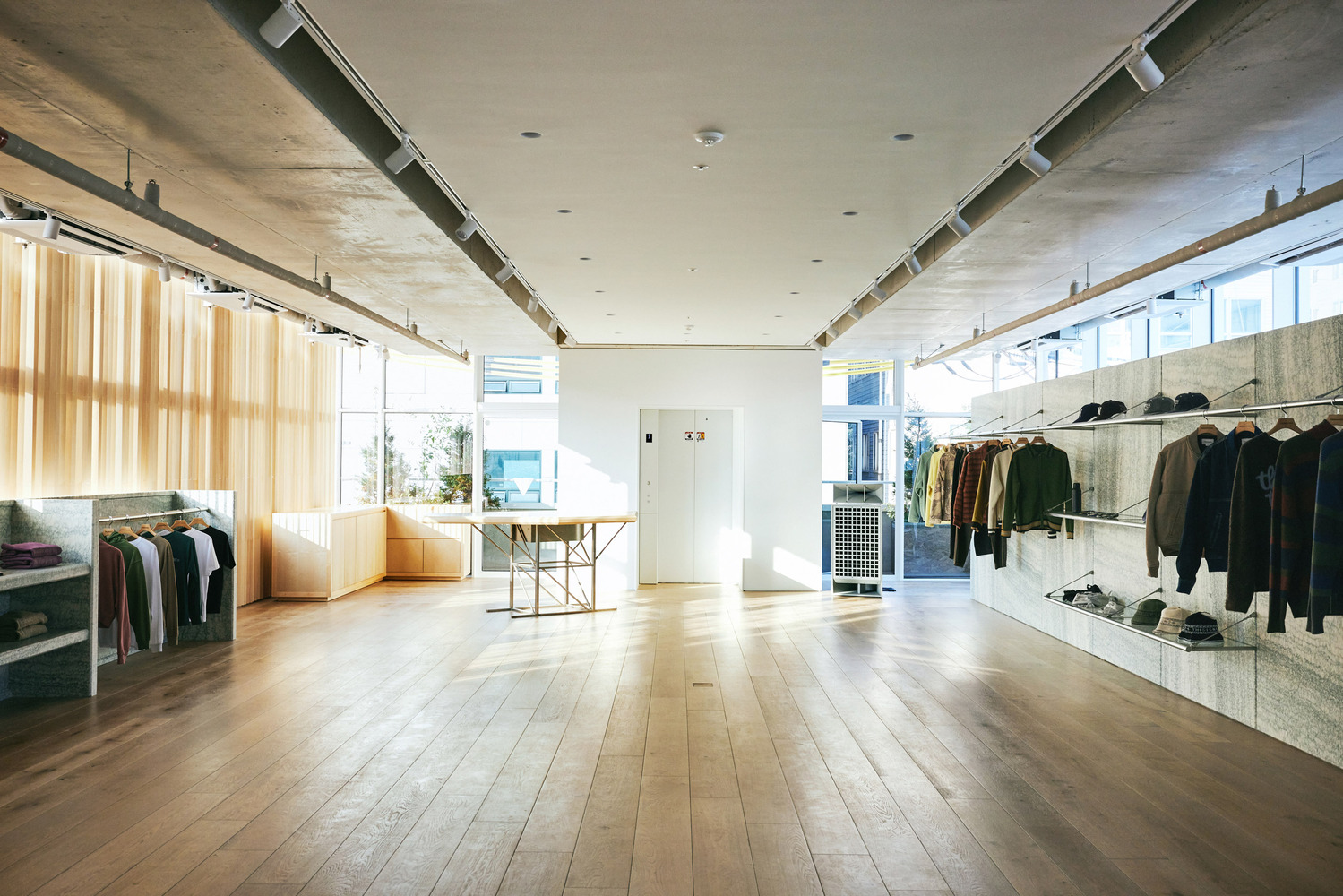 Second floor: wide open plan with hanging rails on both sides, timber slat wall with golden light, plywood display, oak floor