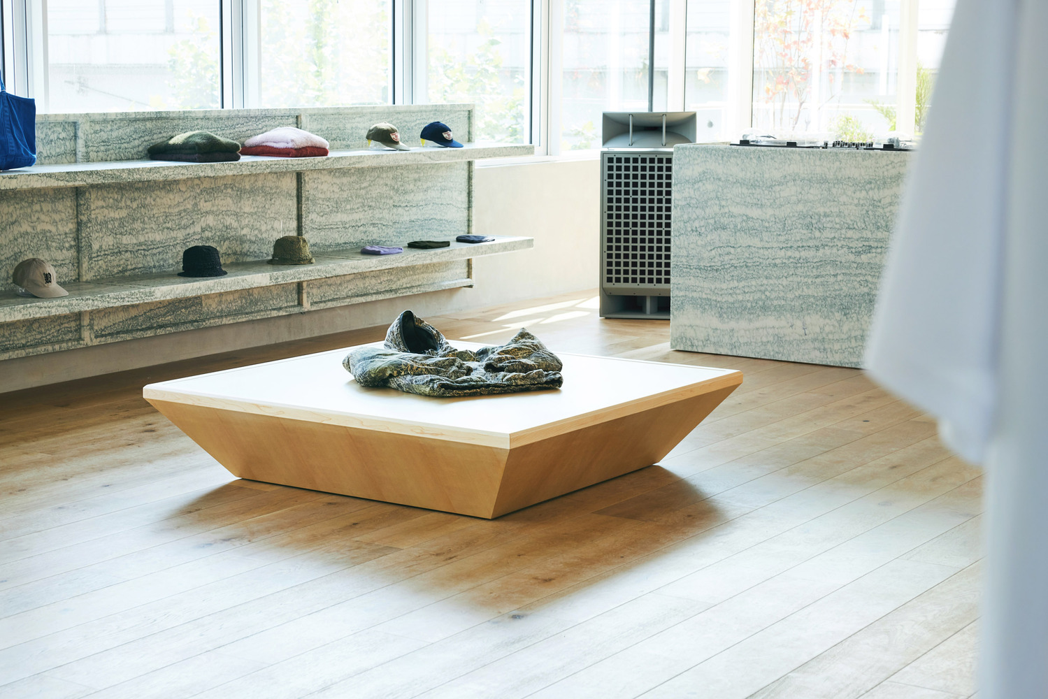 Through-view: wide corridor between two mirrored display rooms, white walls, hanging rails, figures browsing at far end