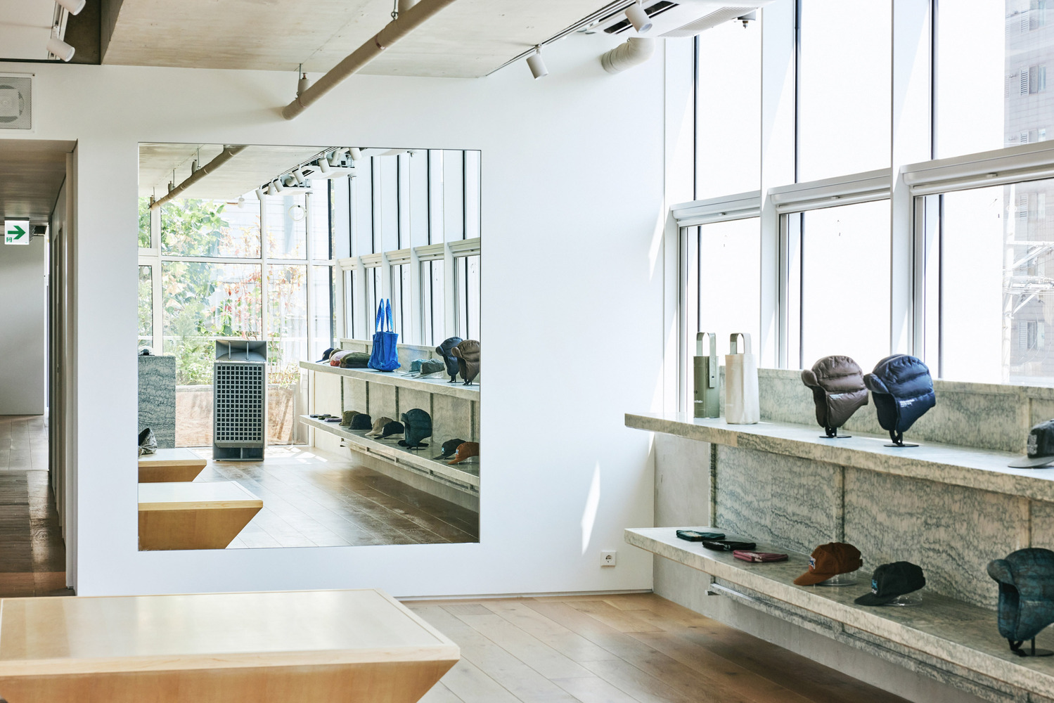 Ground floor from entrance: clothing on hanging rails, wall-mounted display shelves, granite counter, window light, track lighting