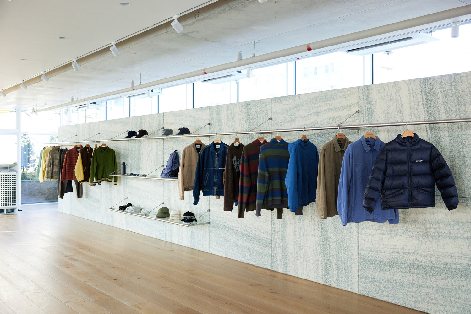 Outerwear wall: jackets and coats hung on tension wire against granite shelving, stepped stone ledge with shoes and accessories
