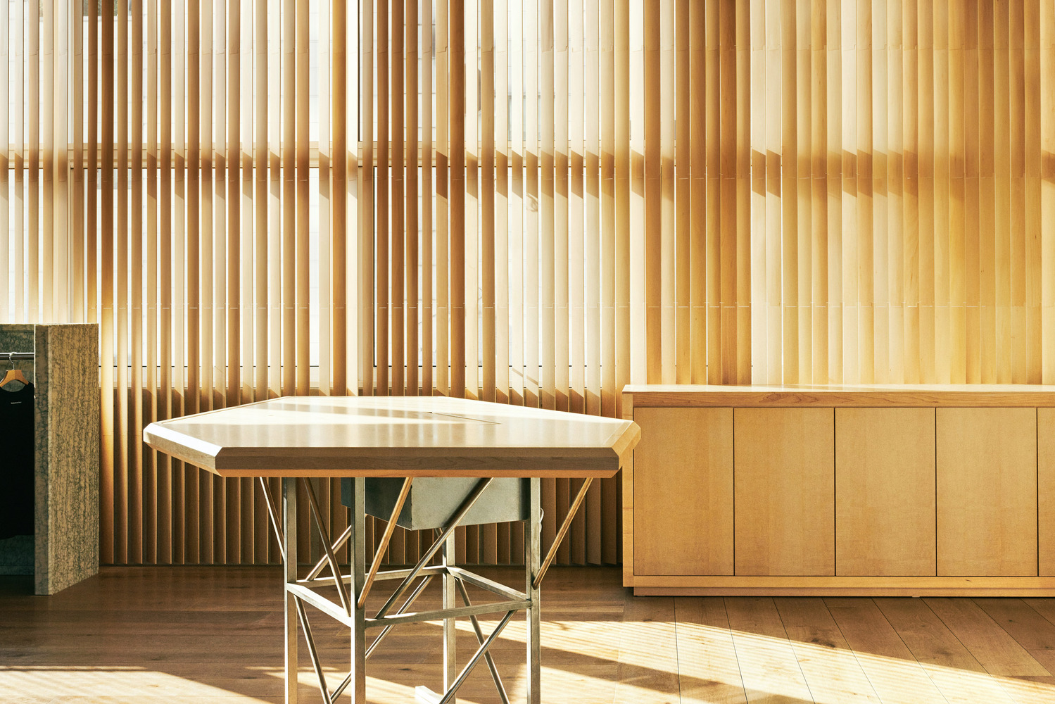 Timber slat wall: golden afternoon light filtering through vertical oak slats, hexagonal display table, oak base cabinets