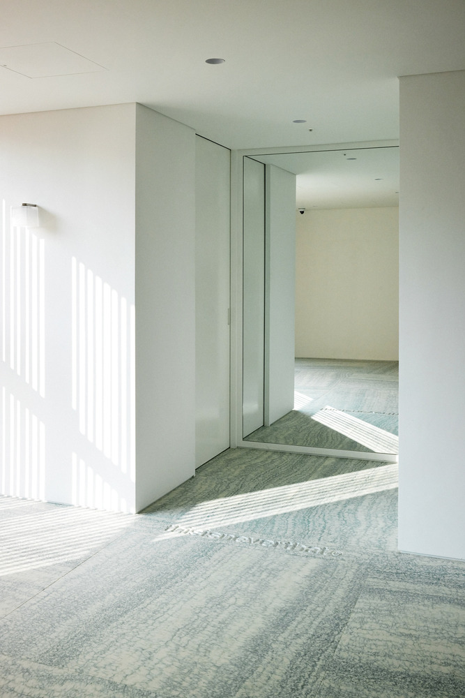Entry threshold: granite stone floor meeting white walls, glass doors, timber slat wall visible beyond