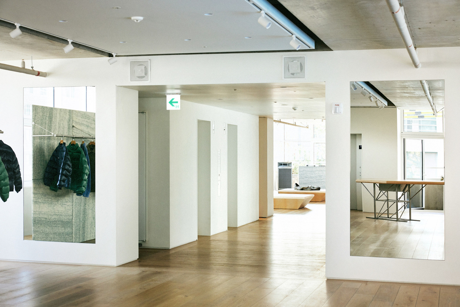 White partitions: framed openings showing hanging garments, plywood display beyond, concrete ceiling, clean and open