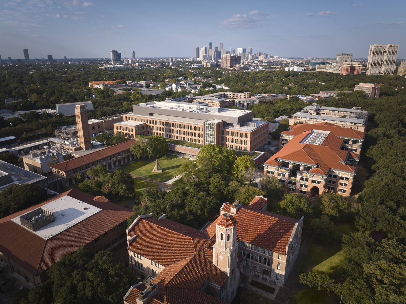 Aerial view of the campus buildings with red clay tile roofs and clock tower surrounded by green lawns and trees