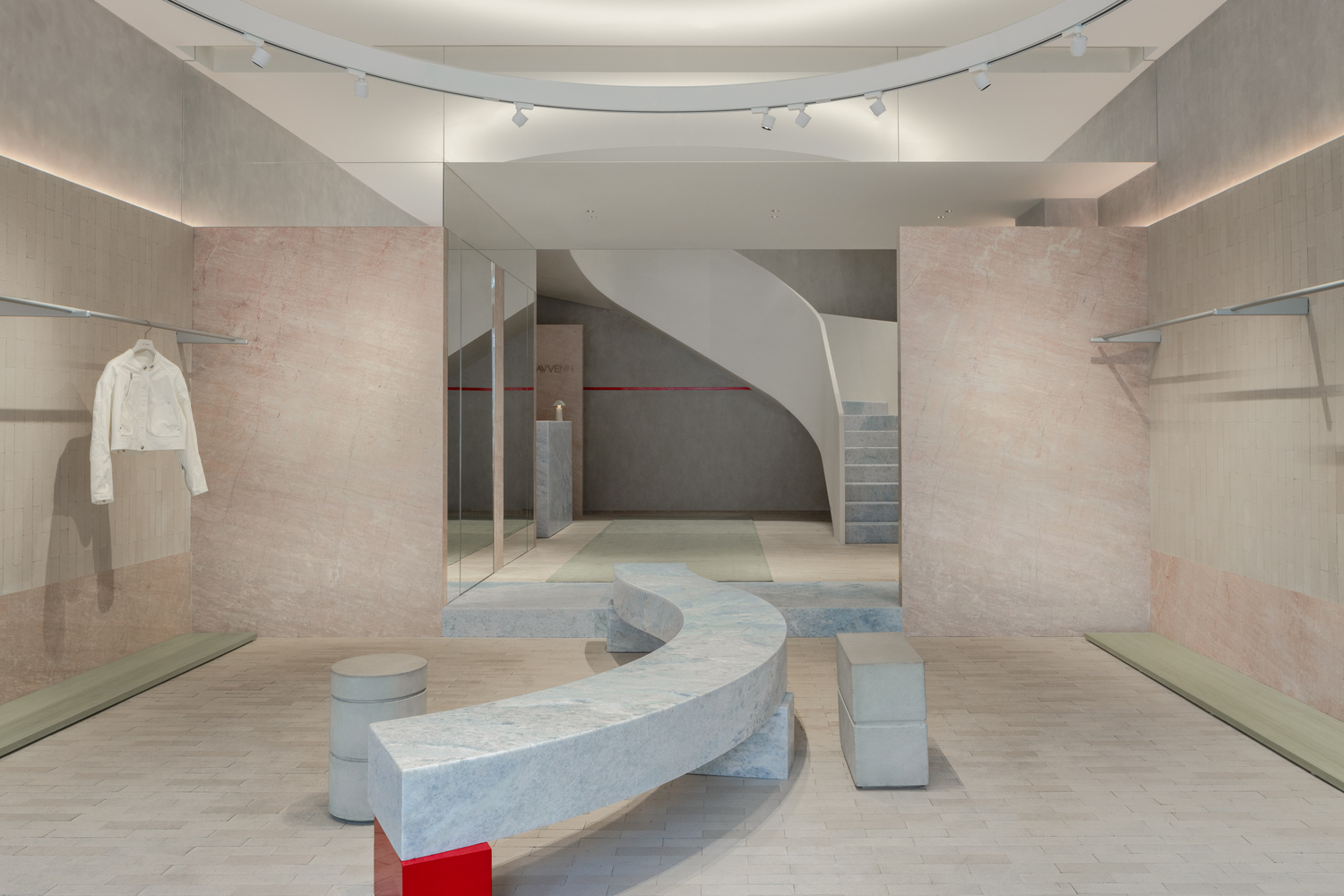 View through glass partition showing curved marble bench and spiraling staircase beneath circular skylight