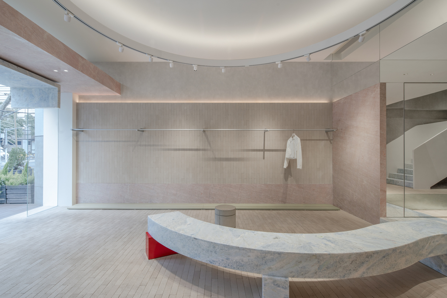 Curved marble bench with red accent beneath hanging rail system along perimeter wall