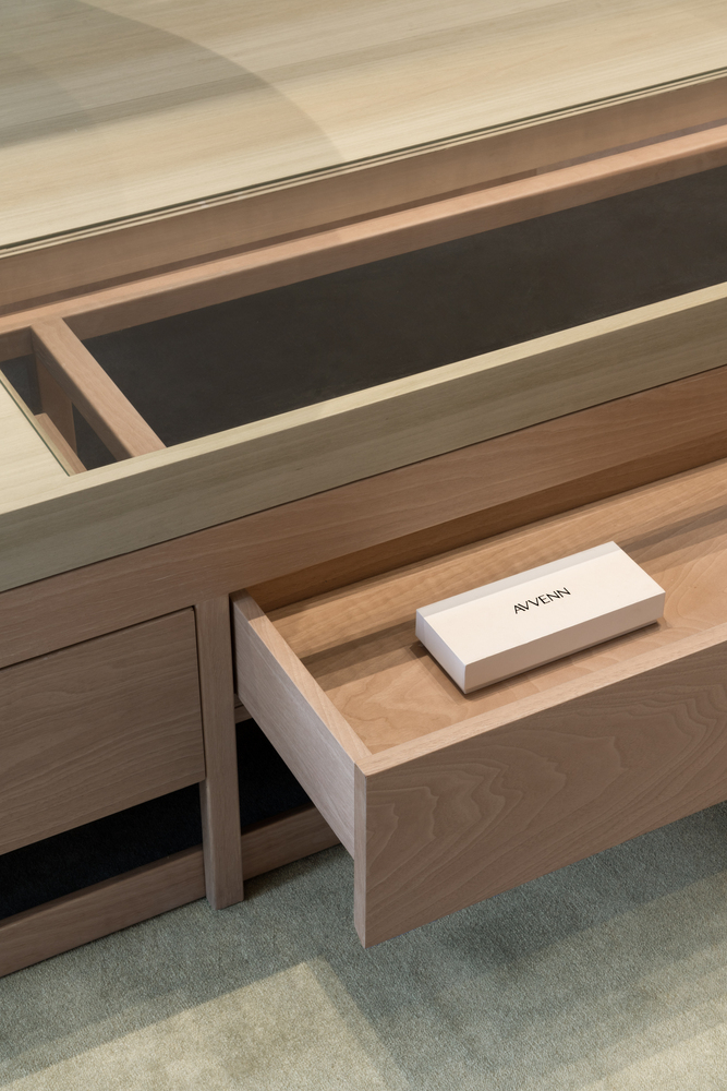 Close-up of an extended wooden drawer revealing compartments with dark felt lining and a white branded box inside