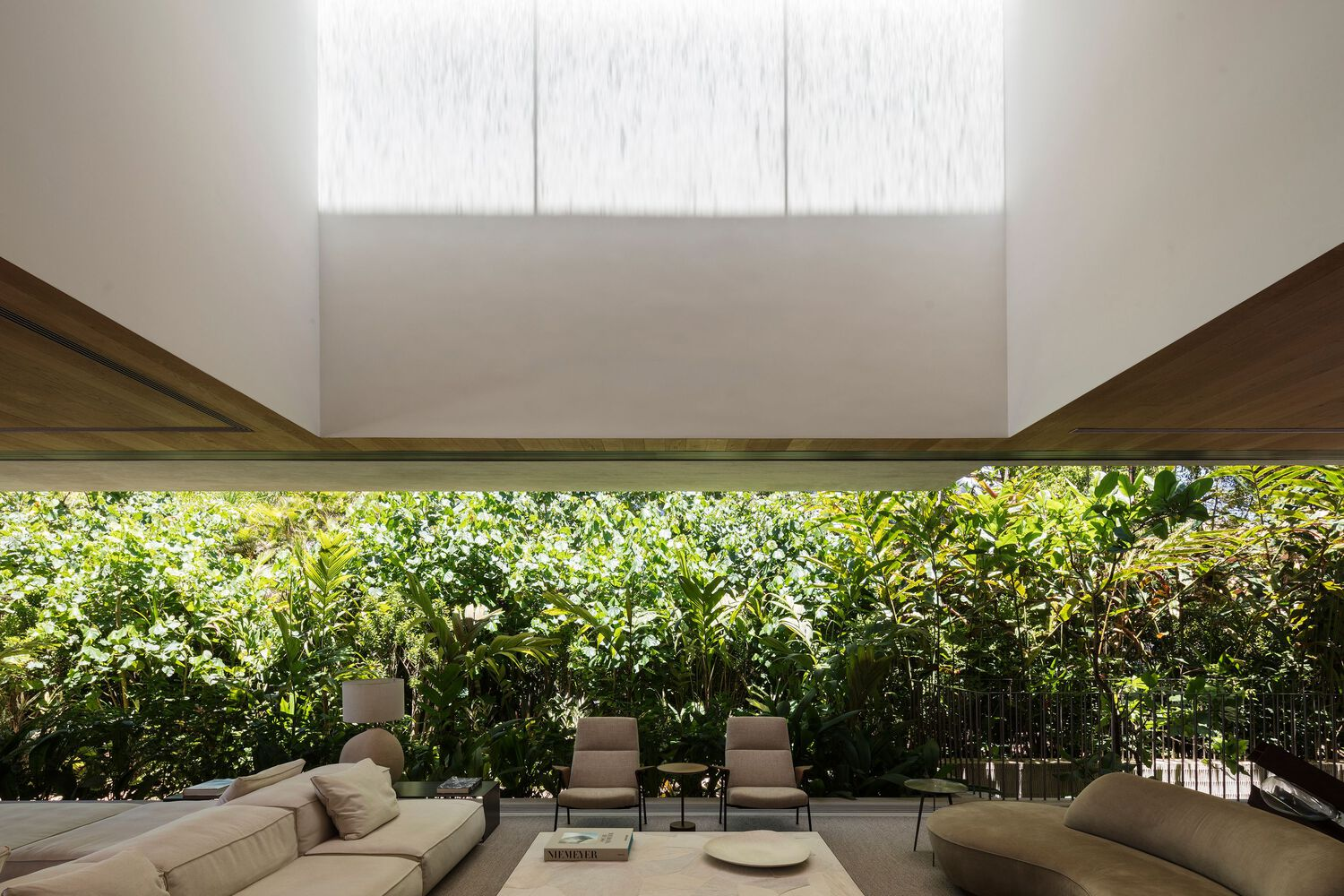 Covered terrace with horizontal window slot framing dense tropical foliage behind seating area