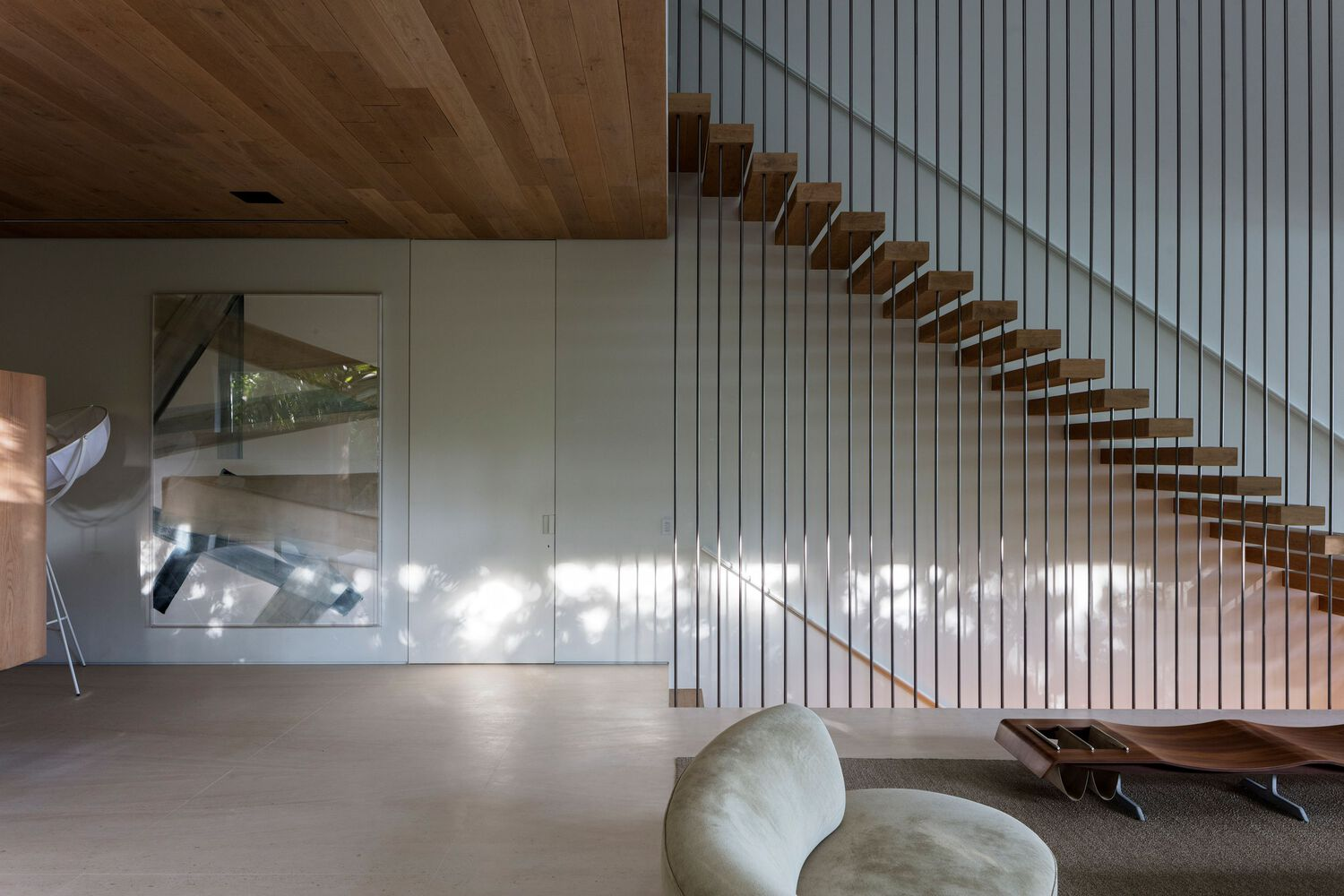 Cantilevered timber stair treads with wire railing and dappled sunlight on the white slat wall below