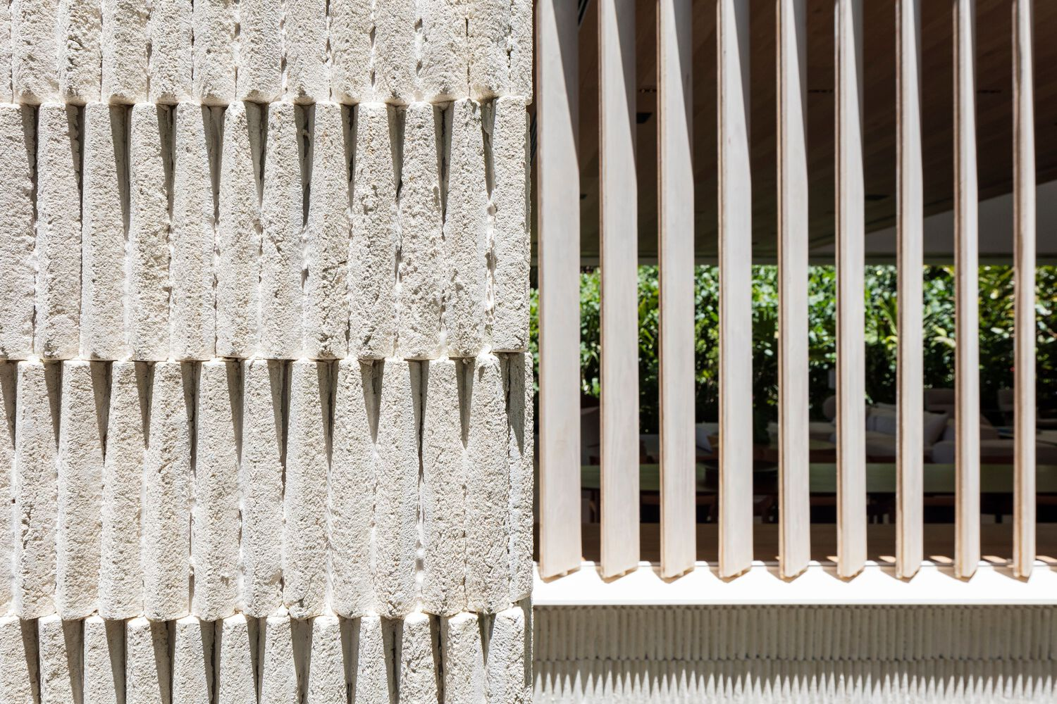 Textured concrete wall with projecting dowels beside a white vertical fin screen in sunlight