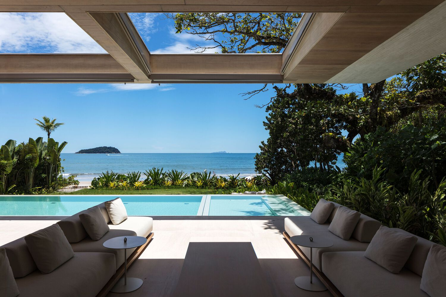 Covered terrace with timber ceiling beams framing a view of the pool and ocean beyond