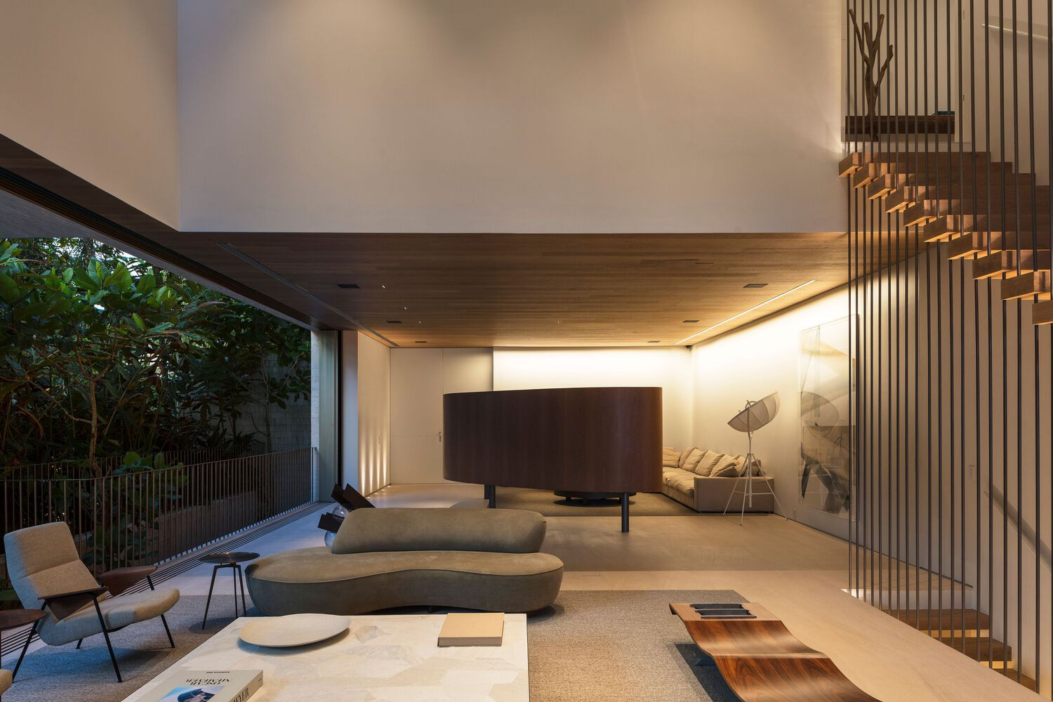 Living area with vertical timber slat screen alongside staircase and full-height glazing opening to garden