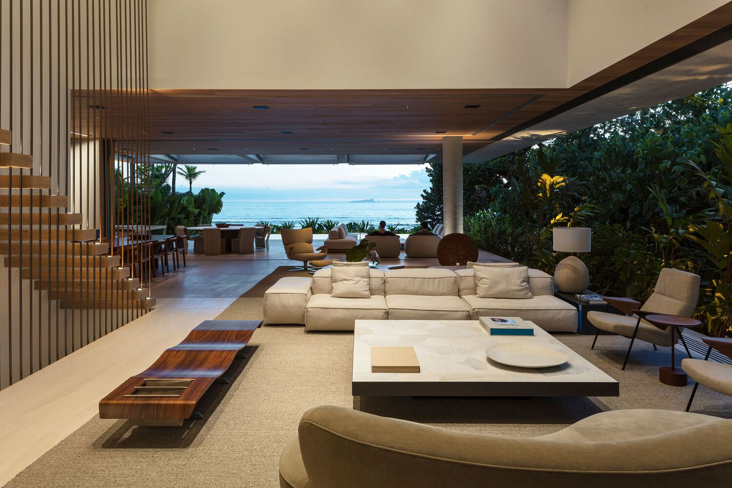 Open plan living space framing ocean views through continuous glazing beneath timber soffit ceiling