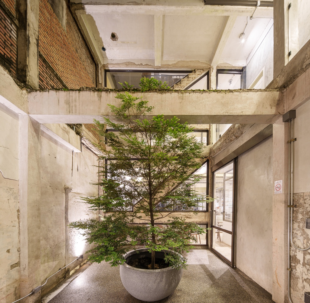 Upper floor landing: glass door to stair, angled concrete walls, street view through glazing, menu board