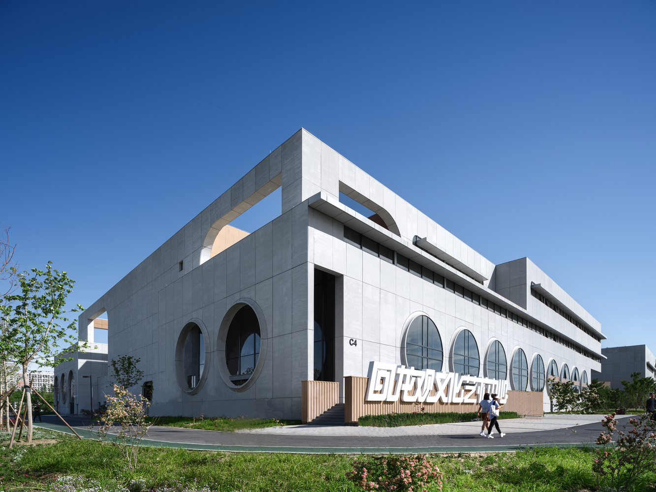 Cultural centre entry: glass curtain wall, timber ramp, Chinese signage, visitors approaching