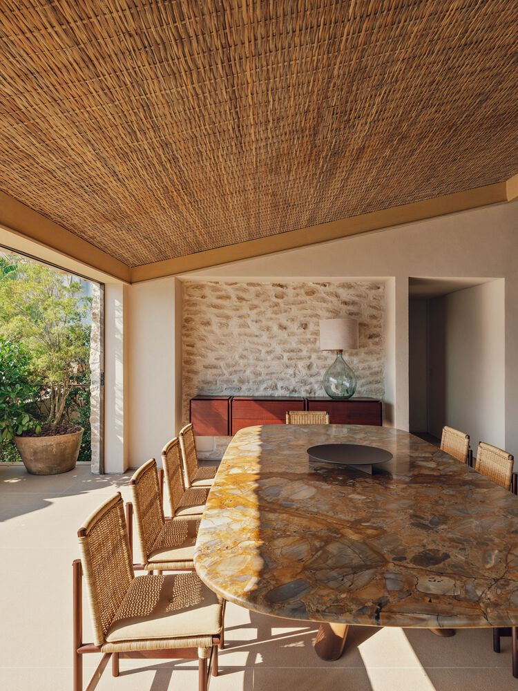Dining room with woven ceiling panels and stone accent wall lit by afternoon sunlight