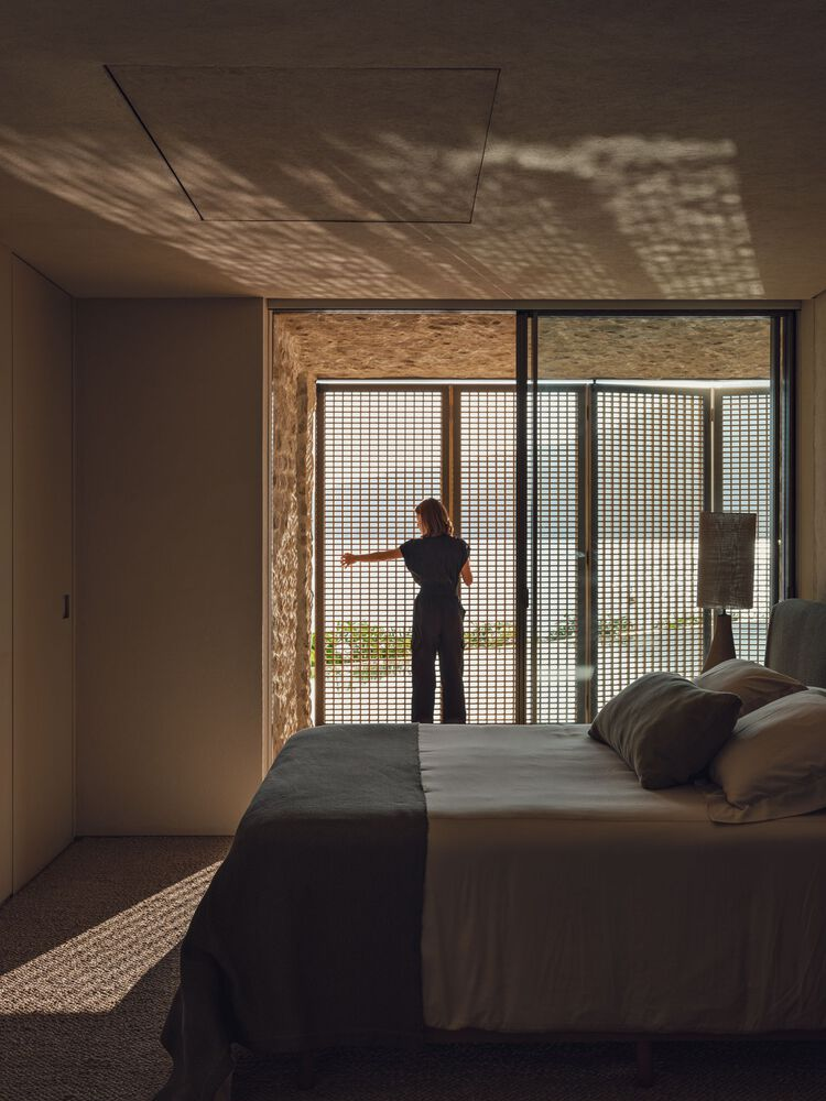Bedroom with a person at sliding glass doors casting dappled shadow patterns across the ceiling