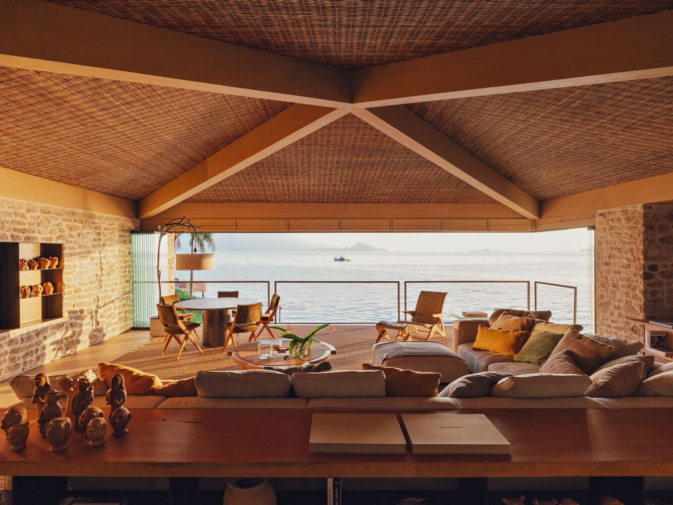 Living area with woven rattan ceiling and timber truss framing ocean view through horizontal opening