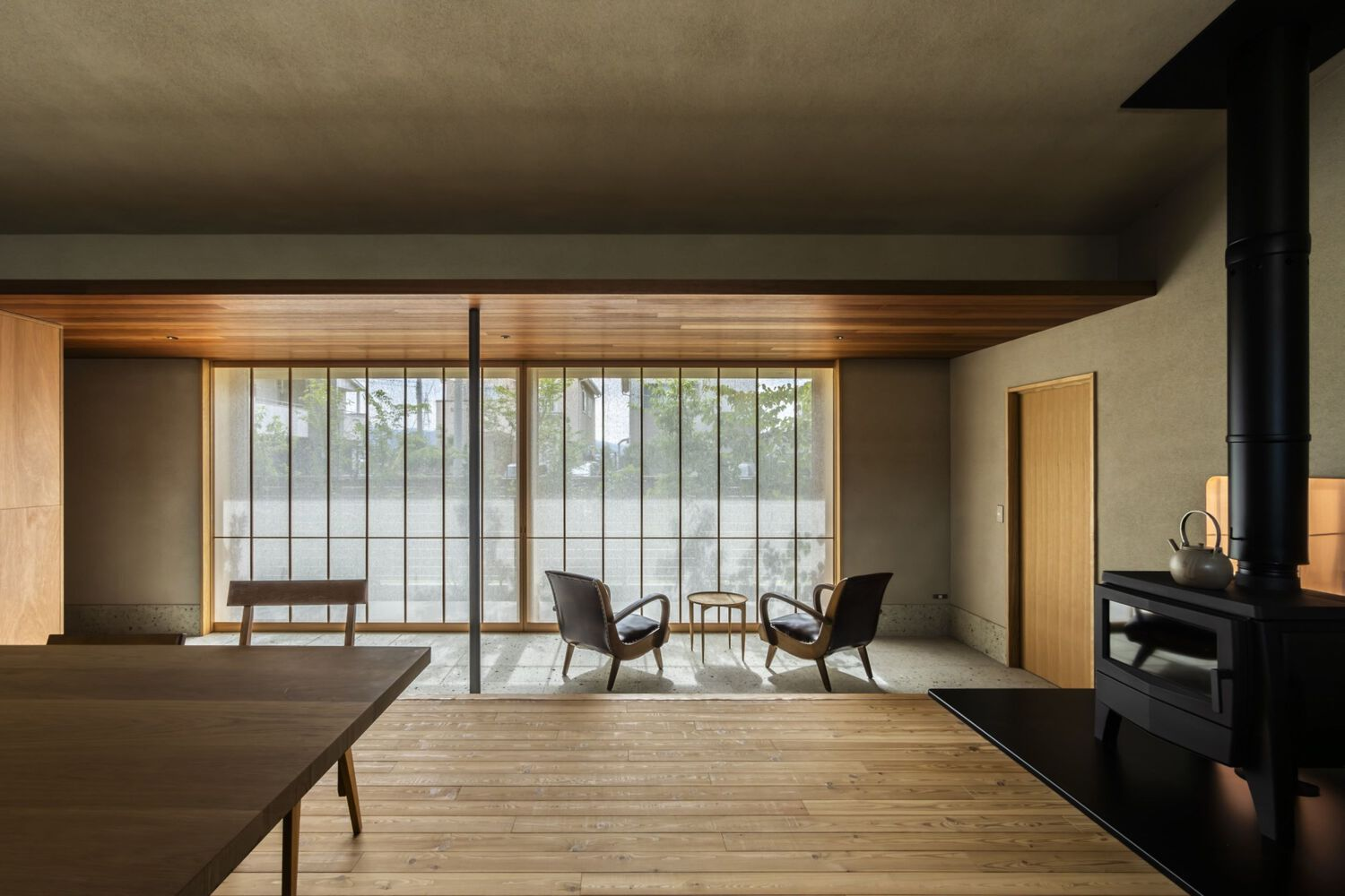 Living area with freestanding wood stove and gridded glass wall overlooking a courtyard garden