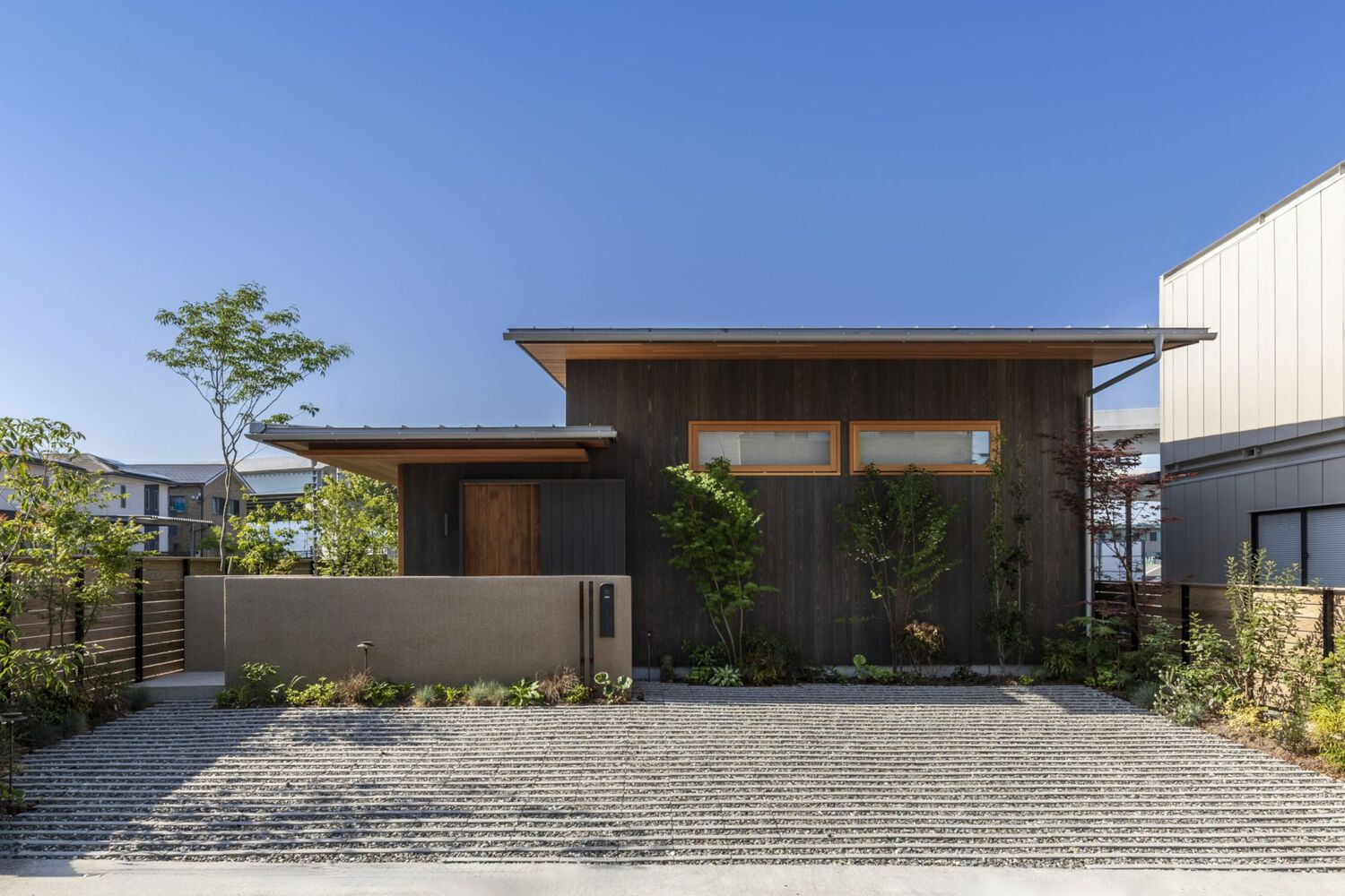 Street view of the residence showing two offset gabled volumes clad in charred timber
