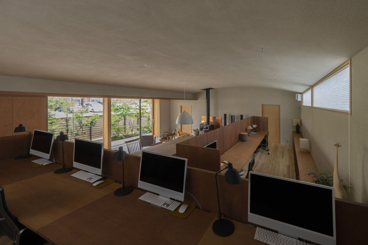 Elevated view of open-plan workspace with rows of desks and monitors beneath a timber soffit