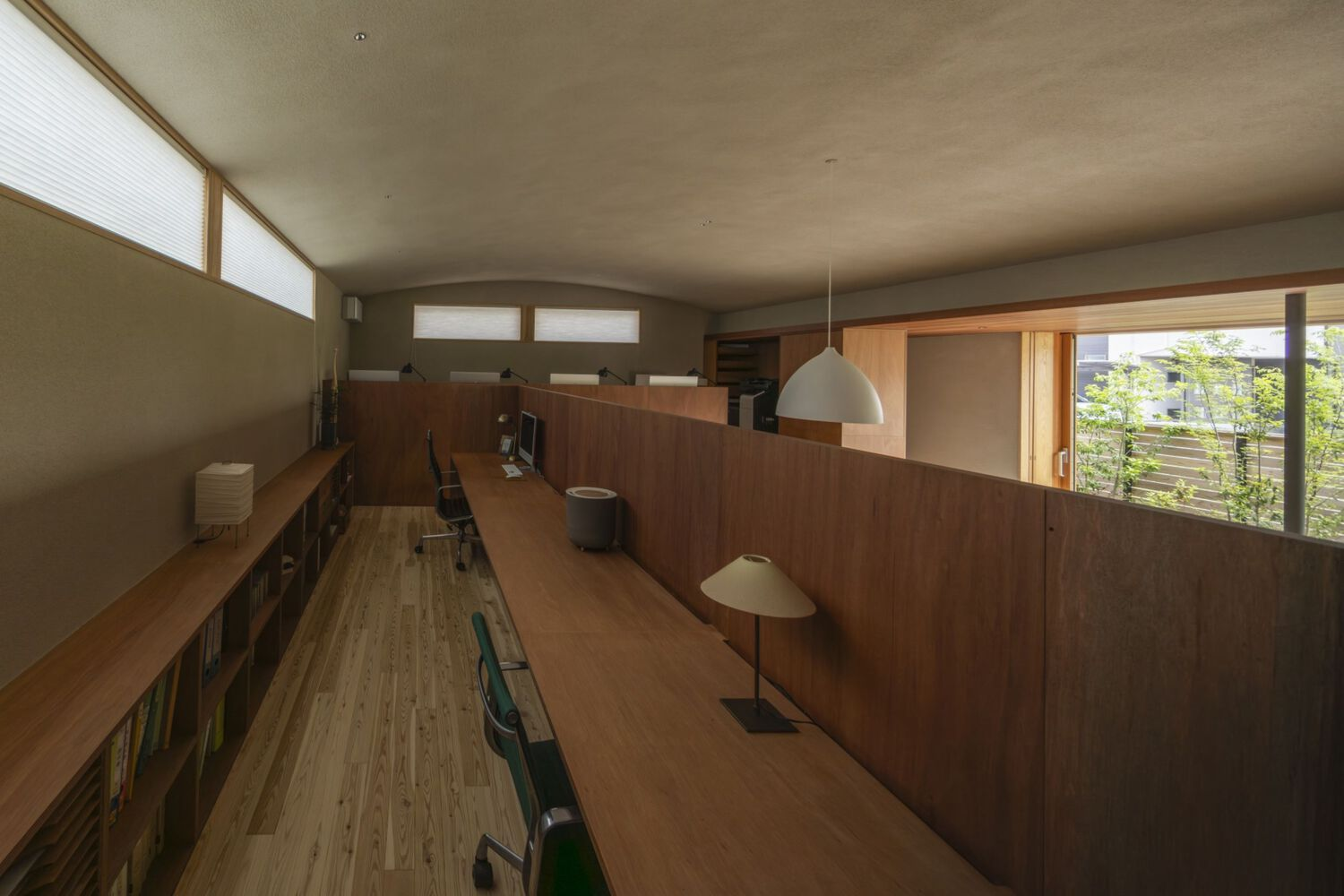 Upper-level workspace corridor with timber desk ledge and high clerestory windows flooding the space with daylight