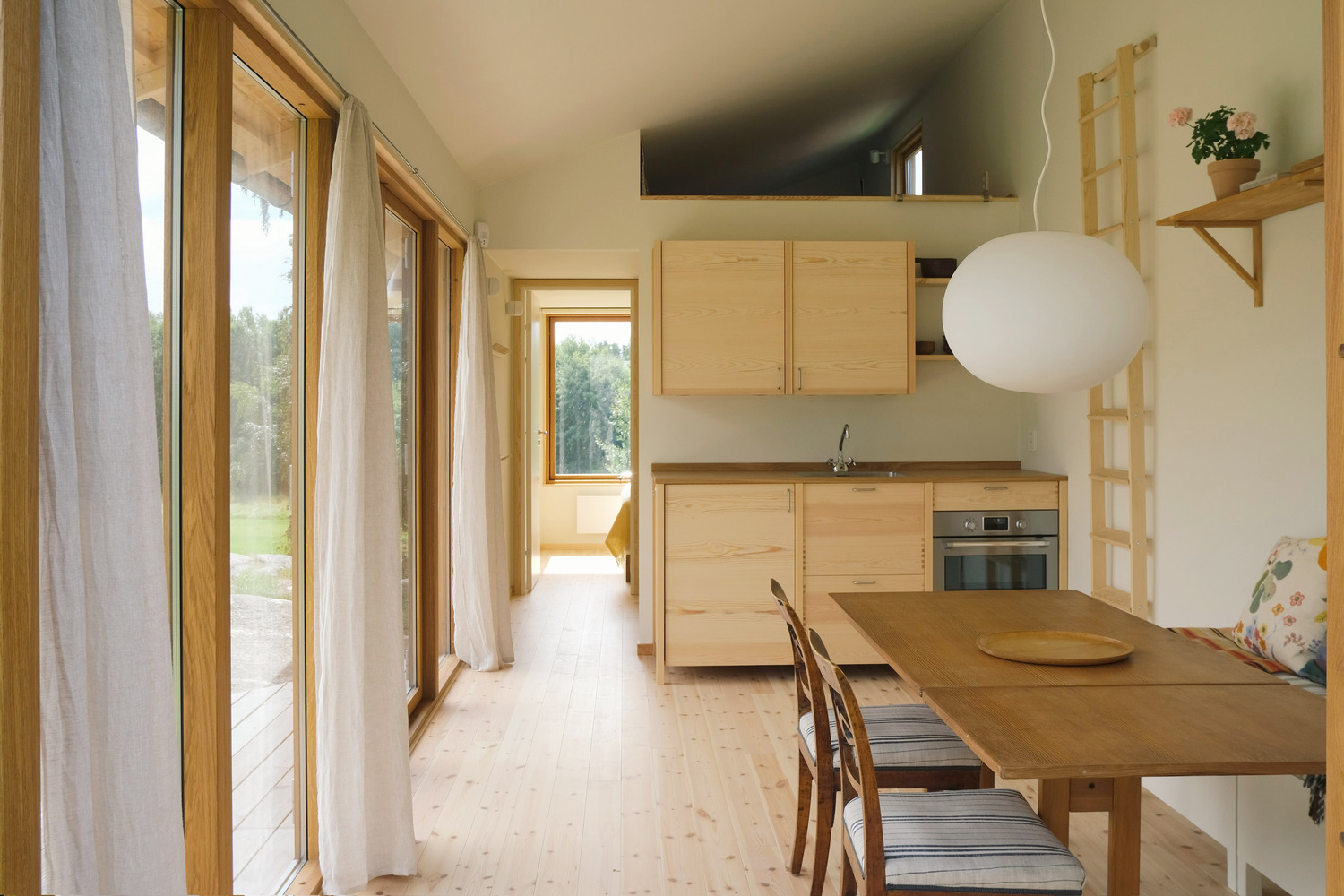Open-plan kitchen and dining space with pale wood cabinetry and continuous glazing along one wall