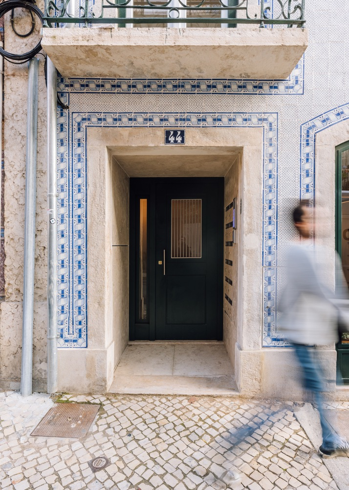 Street entry with limestone surround and blue azulejo tile border as a pedestrian passes by
