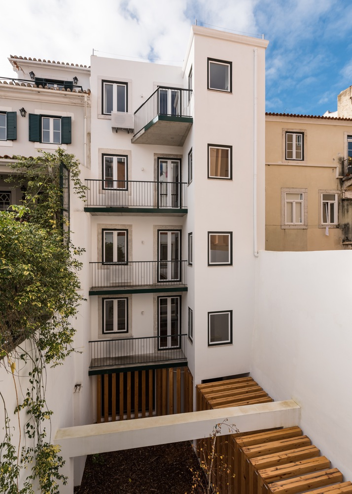 Rear courtyard view showing white facade with stacked balconies and timber screens under blue sky