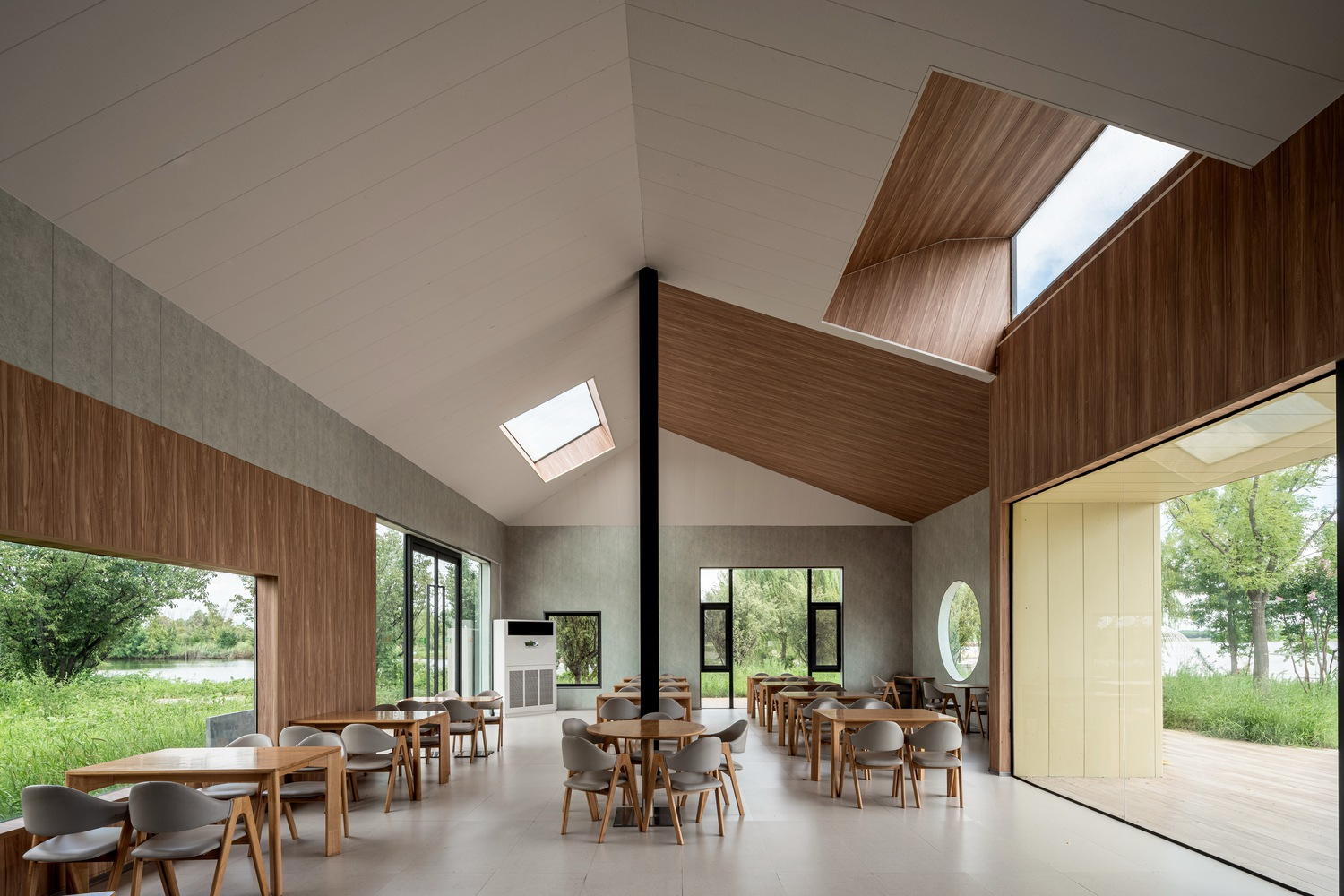 Dining hall interior with pyramidal skylights and timber ceiling panels over polished concrete floor