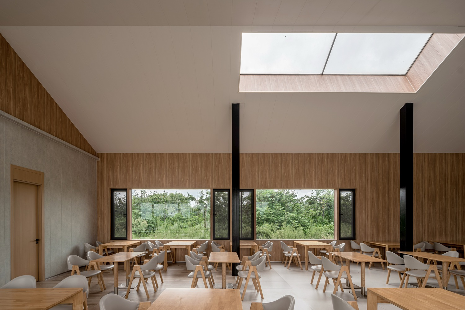 Dining room with horizontal ribbon window overlooking trees and a rectangular skylight above