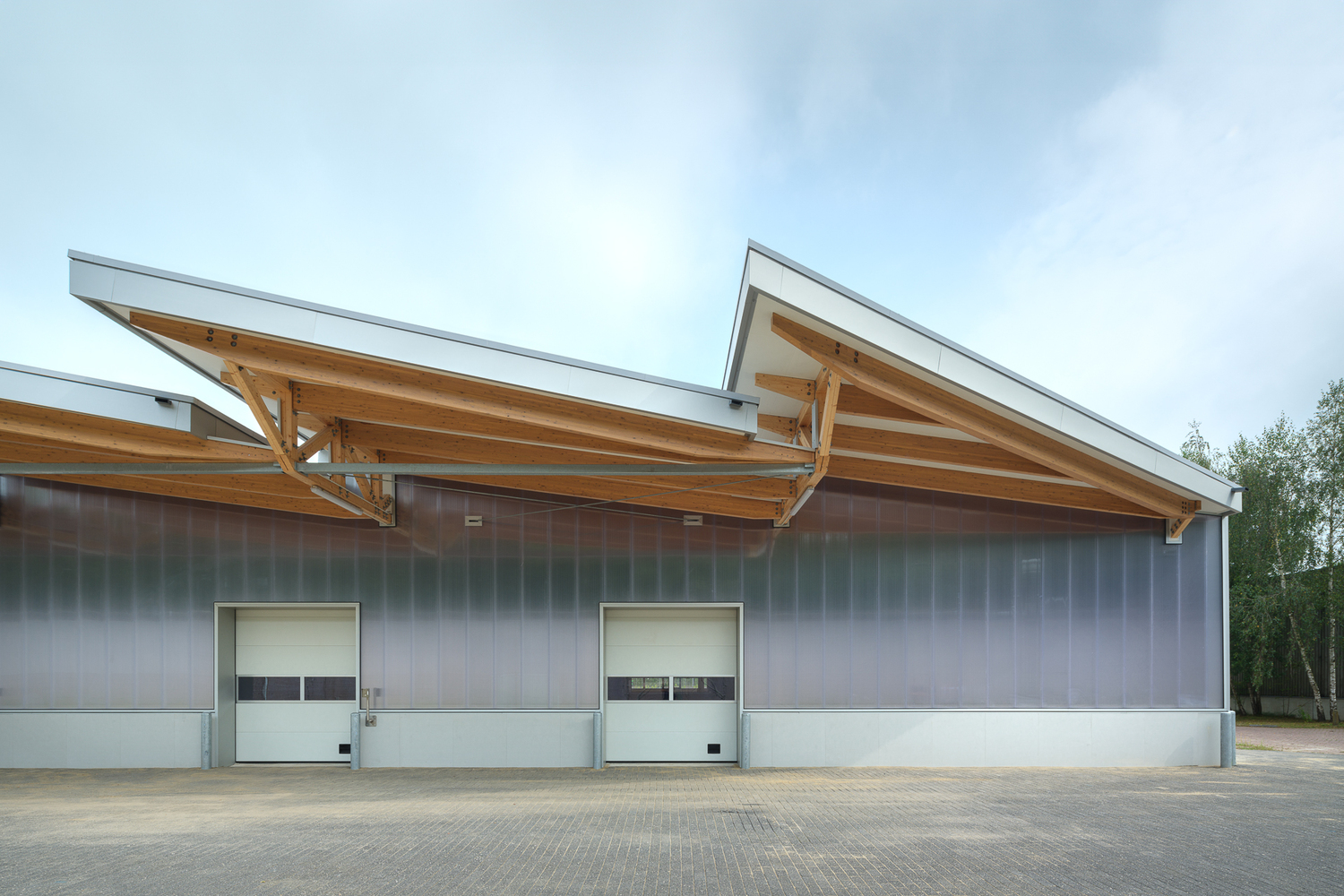 Expedition side: exposed timber trusses extend into canopy over loading dock roller doors
