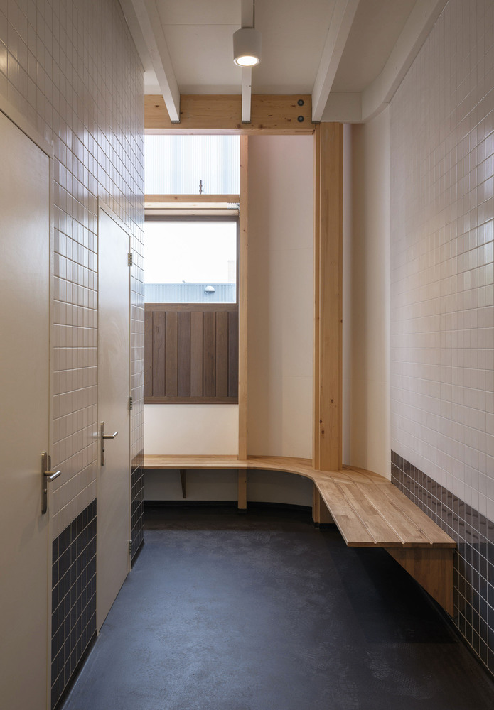 Interior: entry vestibule with timber bench, white tile walls, and clerestory window