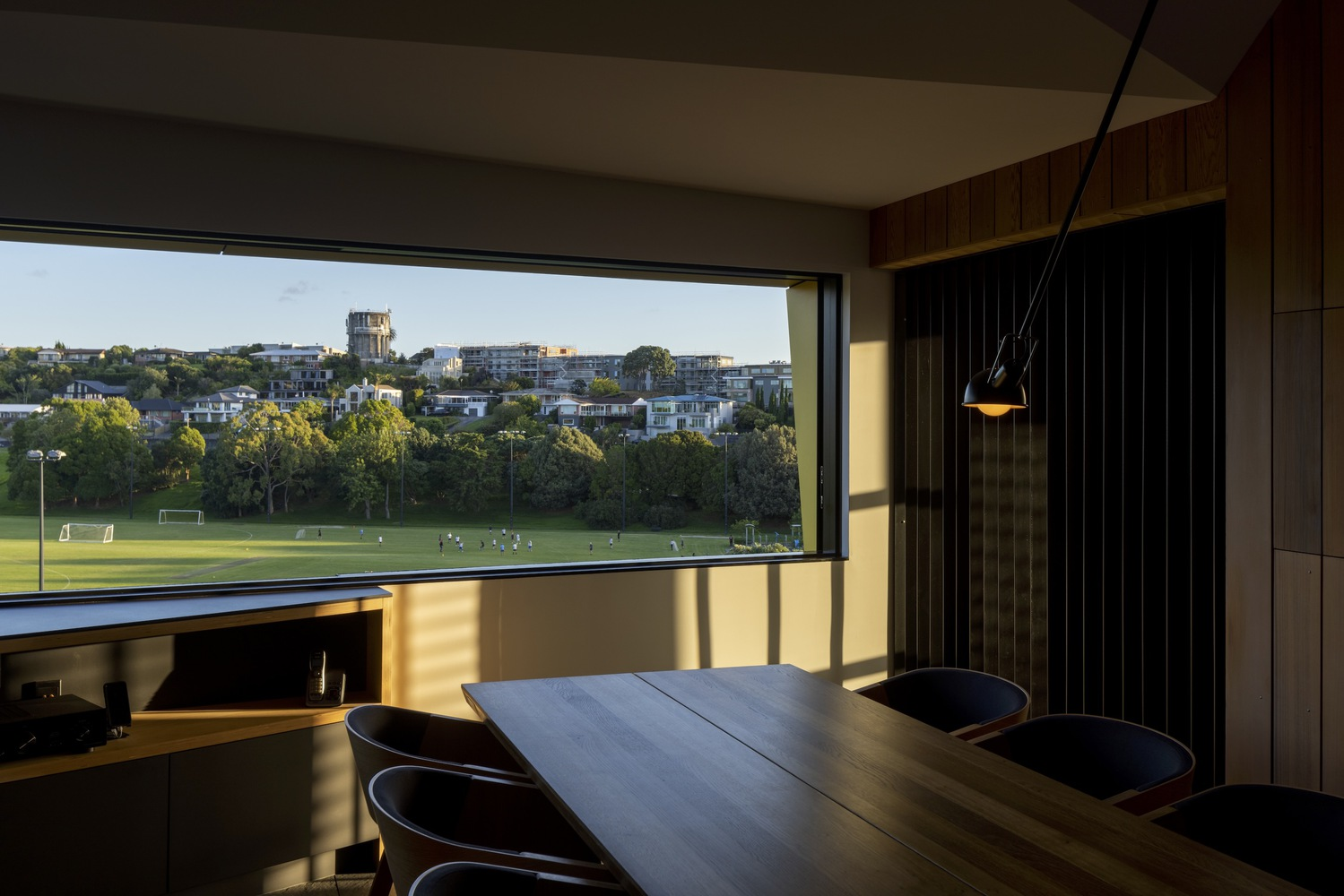 Dining area with horizontal window framing distant parkland views in late afternoon sunlight