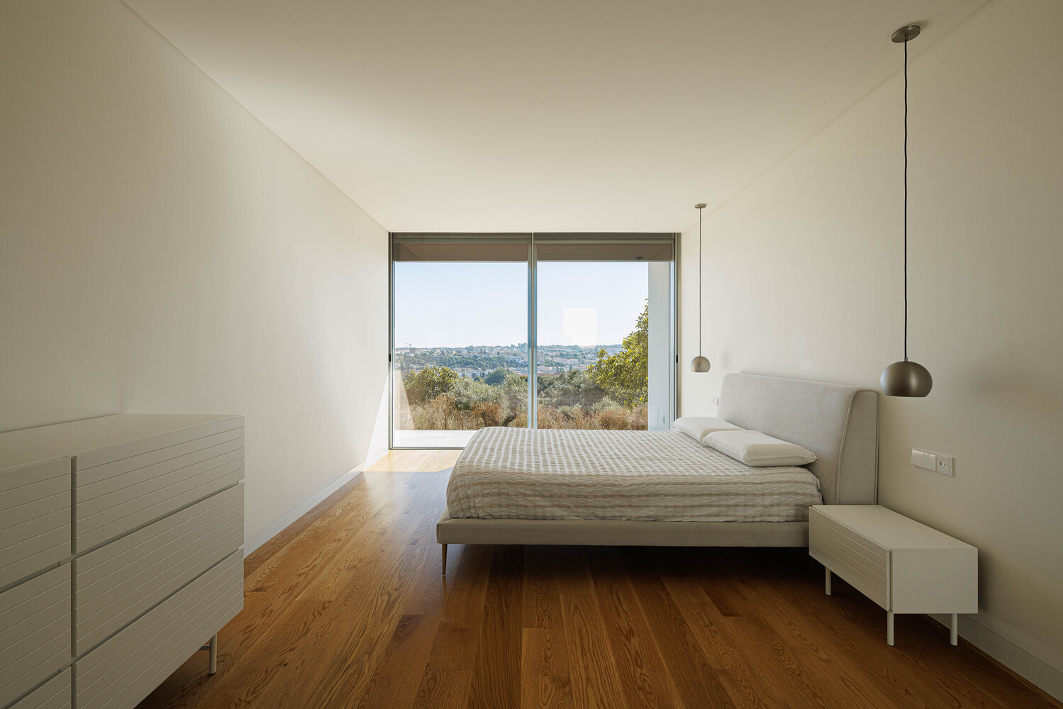 Bedroom with sliding glass door framing views of olive trees and distant hills