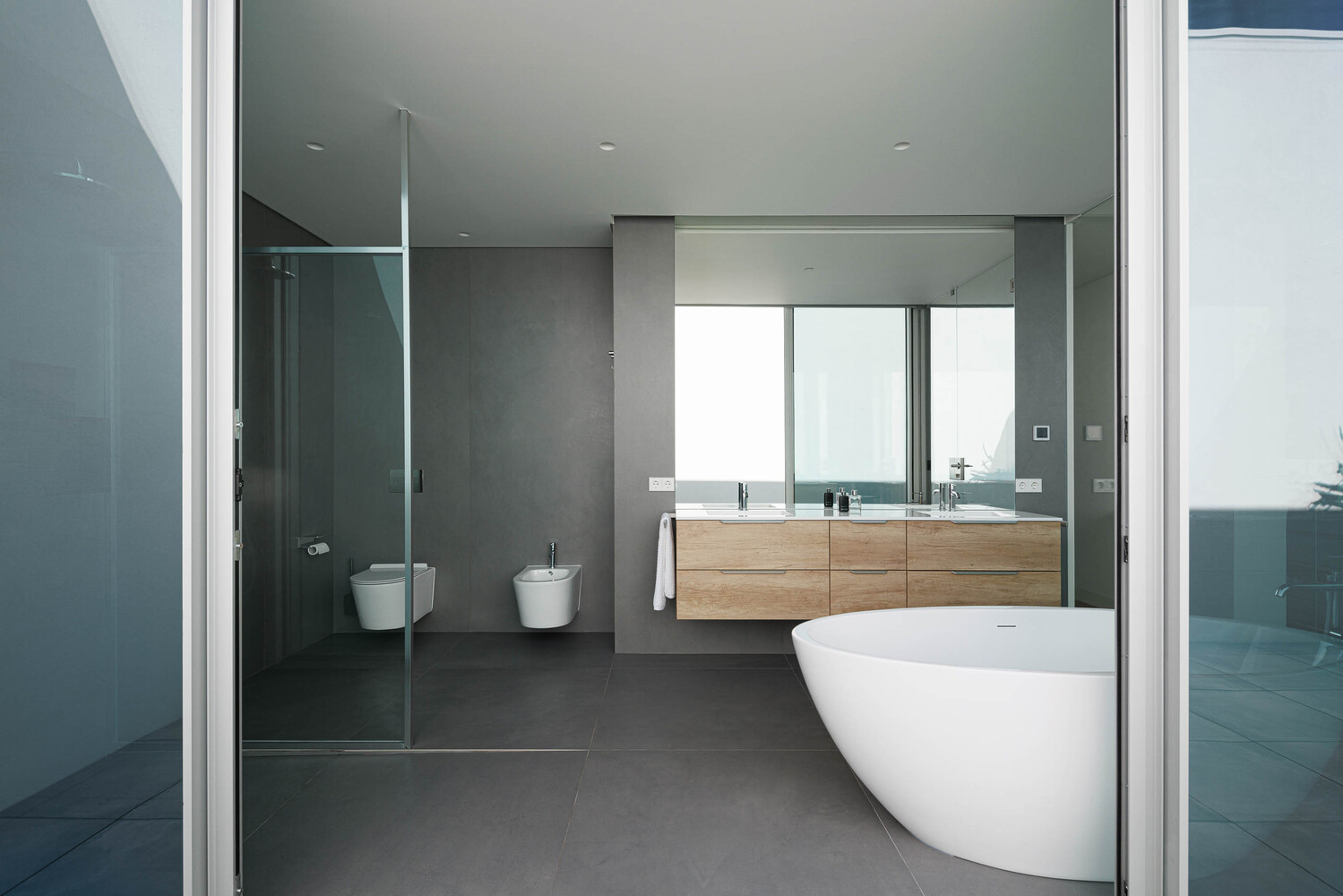 Bathroom interior with freestanding tub, timber vanity, and glass shower enclosure under diffused daylight