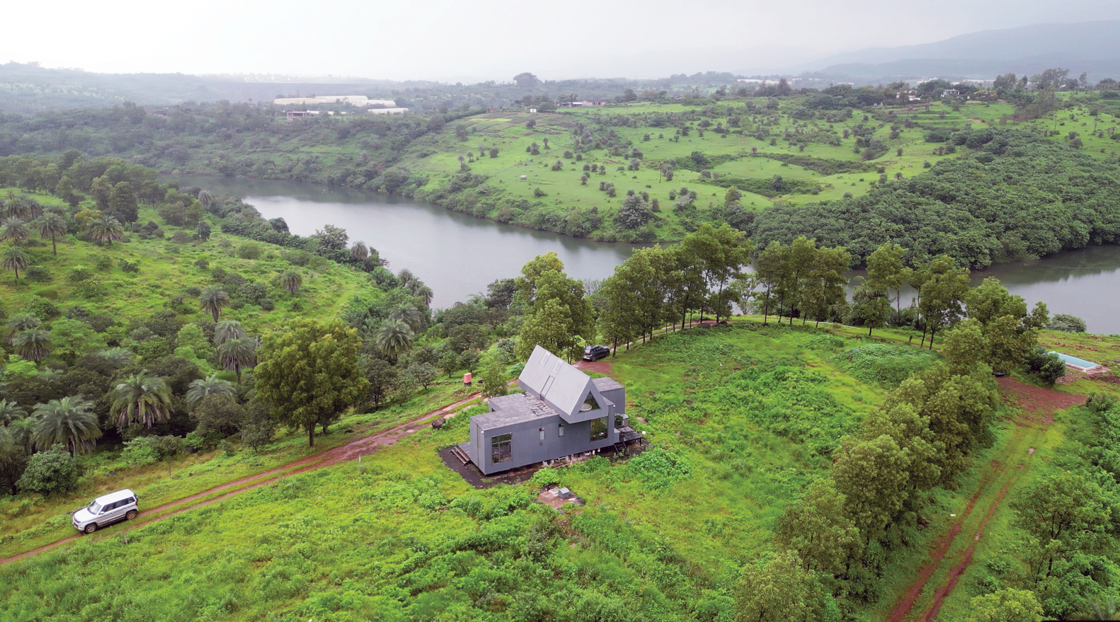 Aerial view of the house on a hilltop plot overlooking a river and green farmland