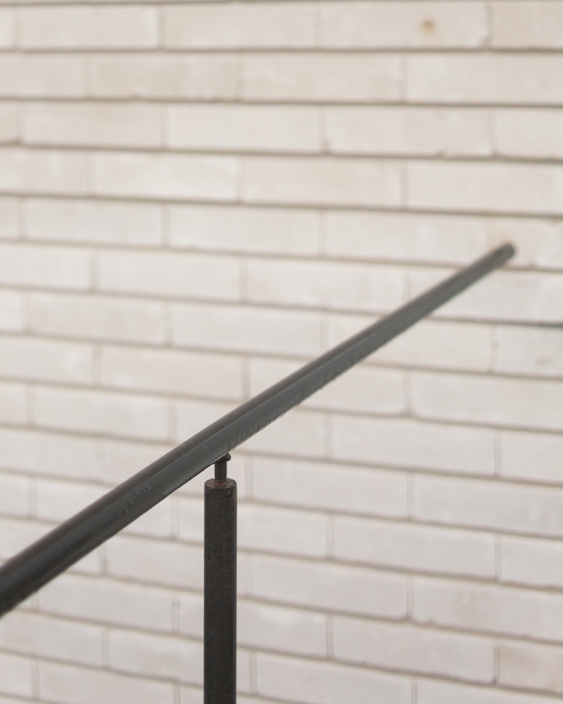 Handrail detail: black steel railing against pale brick wall