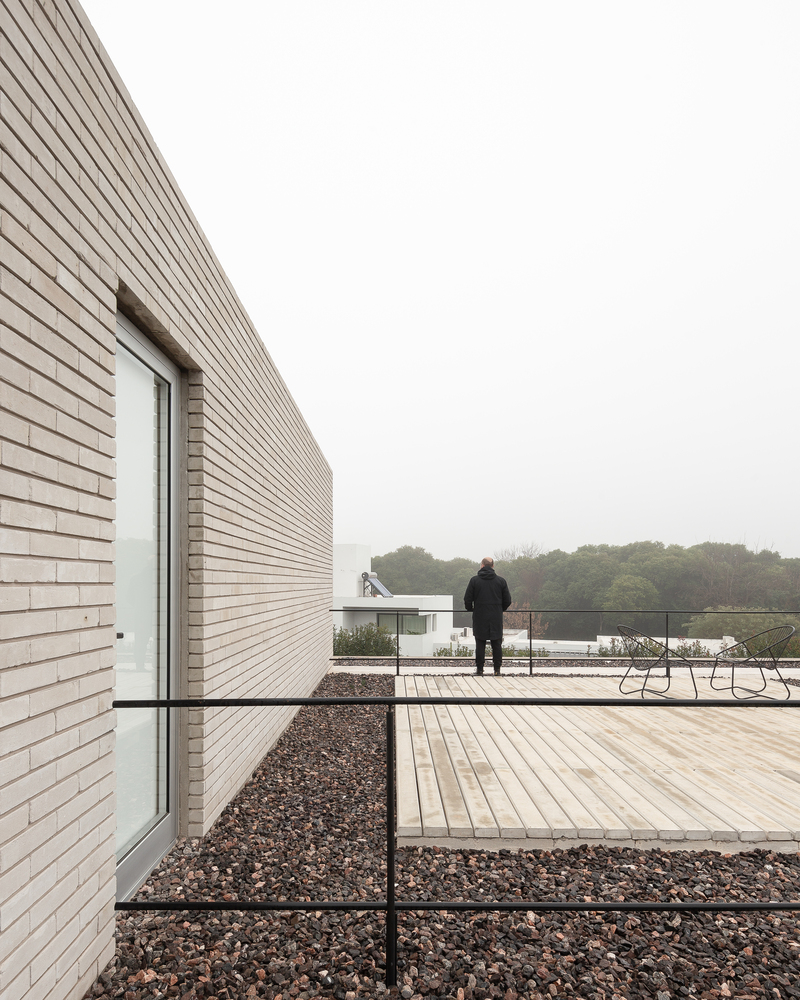 Terrace perspective: figure walking along the timber deck, brick parapet, trees beyond
