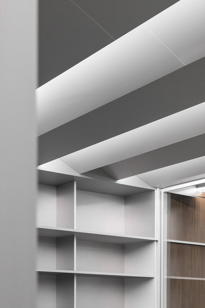 Ceiling: white baffles with gaps between, grey structure above, shelving unit edge at the corner