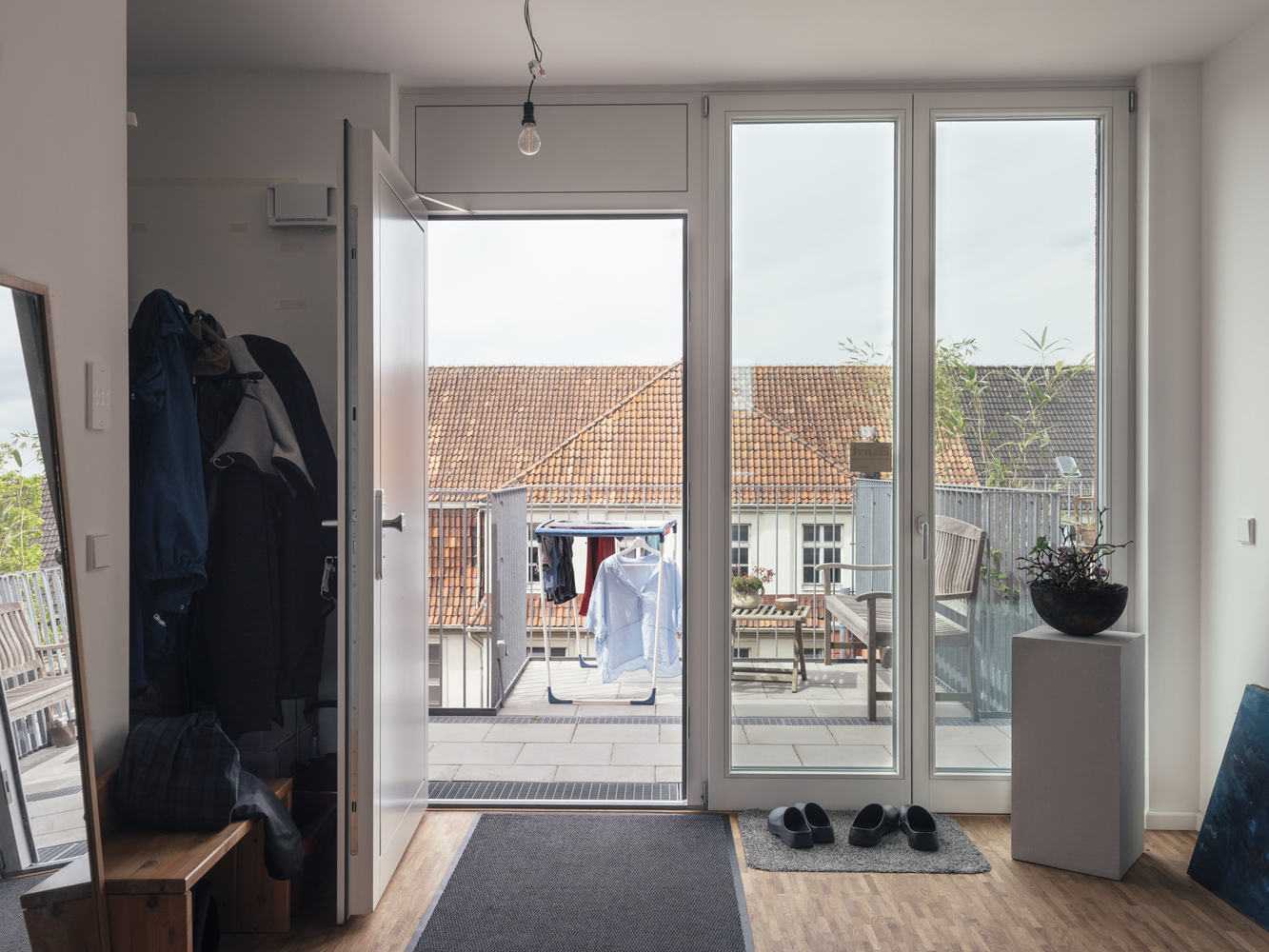 Entry vestibule with glazed doors opening to a rooftop terrace overlooking clay-tiled roofs