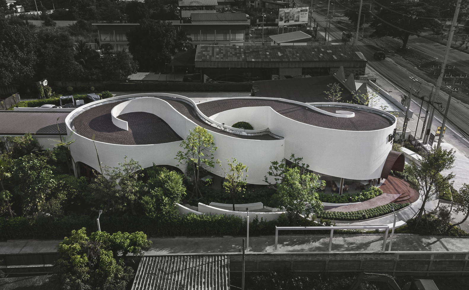 Elevated view of the cloverleaf roof set among trees along a street at dusk