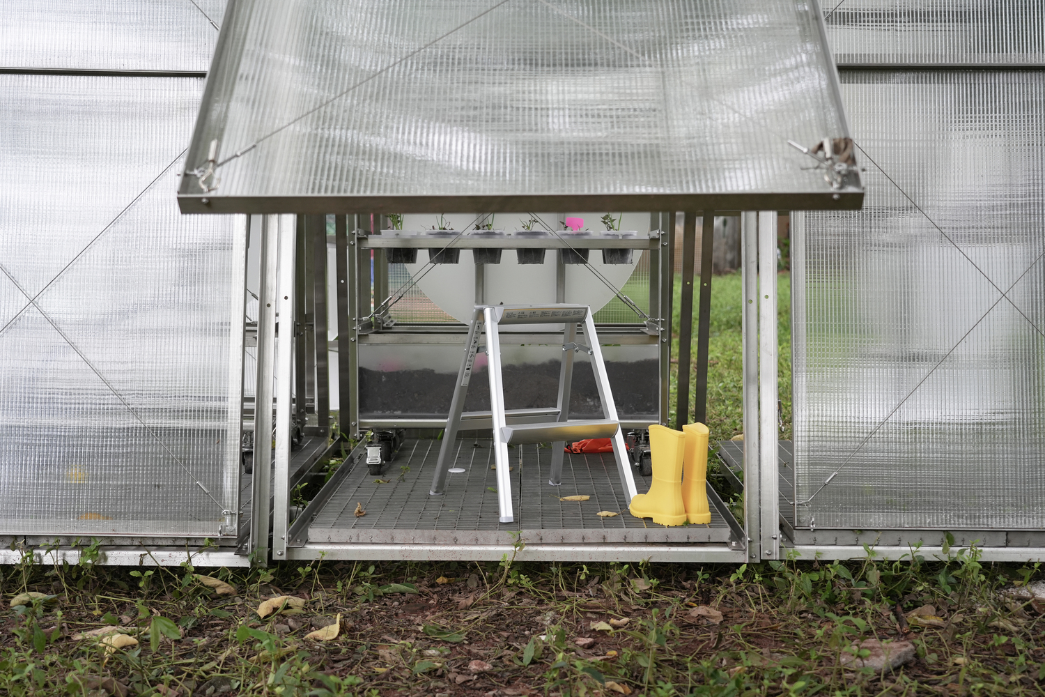 Ground-level view showing yellow boots and cultivation tools stored beneath the raised frame platform