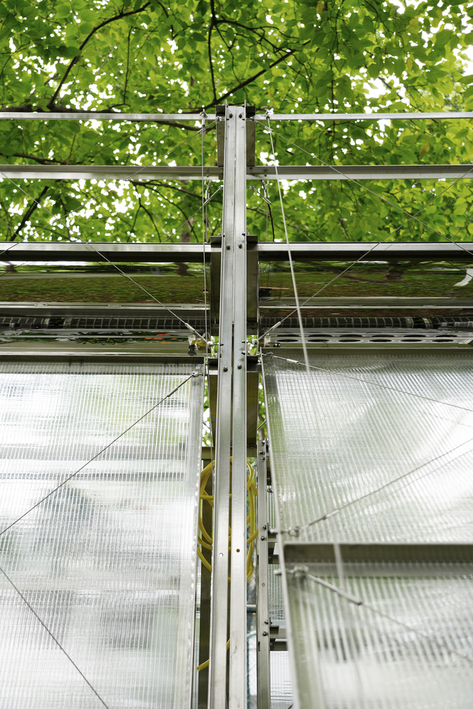 Detail of aluminum column junction with cable bracing and translucent polycarbonate sheets behind