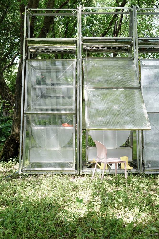 Exterior elevation of translucent greenhouse panels with white plastic chair visible inside beneath mature trees