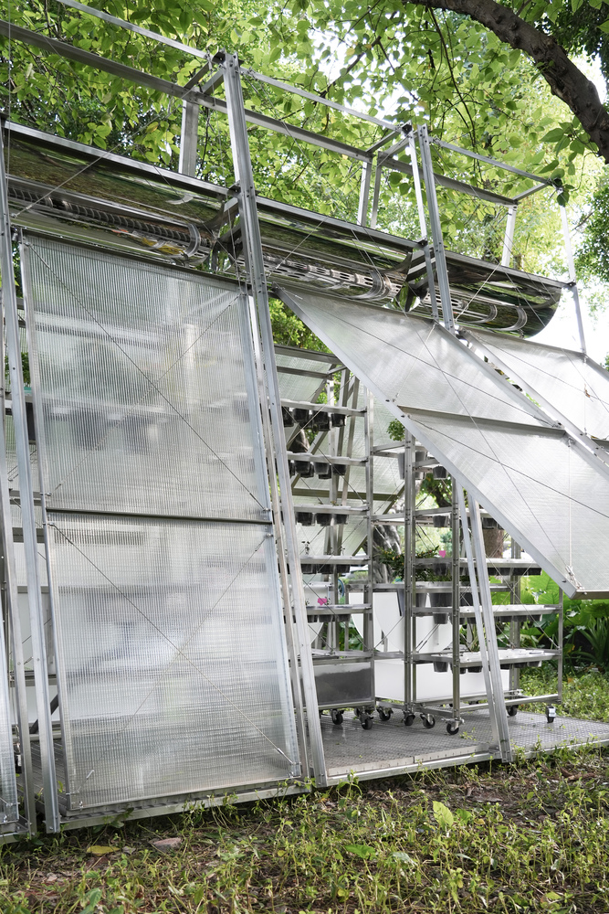 Detail of the angled translucent wall panels meeting the tubular steel structure with foliage beyond