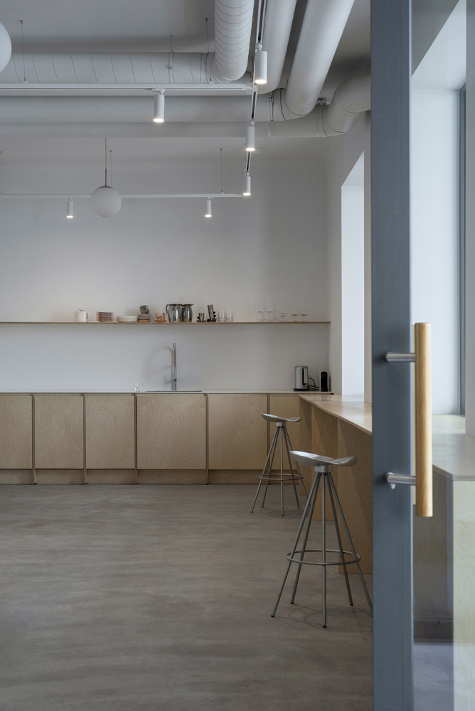 Kitchen with light birch cabinetry, exposed ductwork and pendant lights hanging from the white ceiling