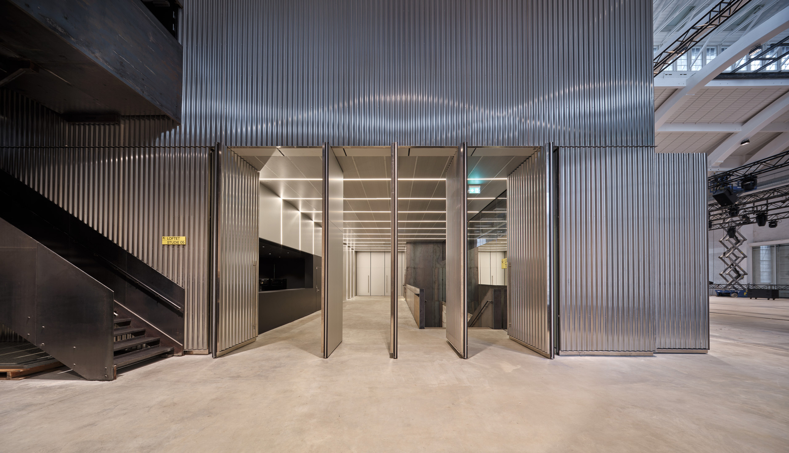 Corrugated metal wall with tall folding doors opening to an interior space with polished concrete floors