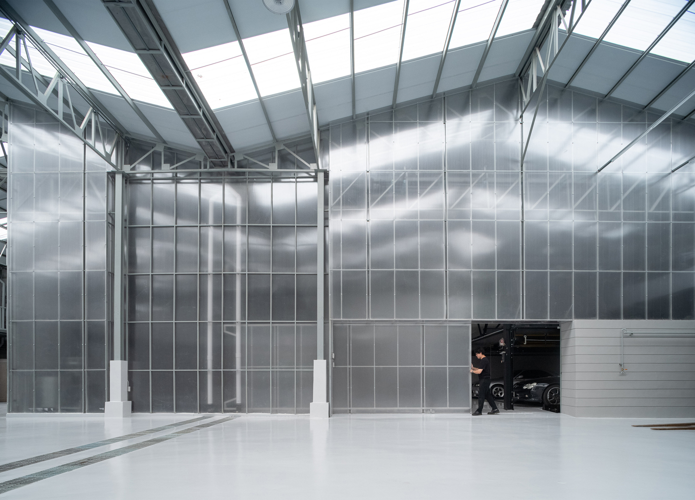 Interior hangar space with translucent polycarbonate walls and exposed steel truss ceiling